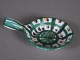 a green and white bowl with a spoon in it