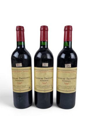 three bottles of red wine sitting next to each other on a white surface