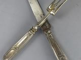 pair of silver plated knives and a fork on a white surface