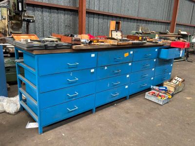 un établi bleu dans un entrepôt, sur lequel sont posés de nombreux outils