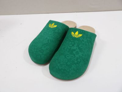 green slippers with yellow adi logo on them sitting on a white surface