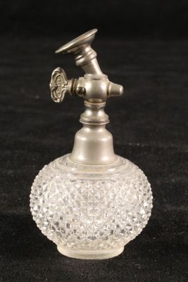 a small glass vase with a metal handle on a black surface