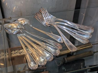 de nombreuses cuillères et fourchettes en argent dans une vitrine