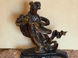 bronze figurine of a woman sitting on a marble table