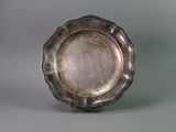 an antique silver plate on a stand against a gray background