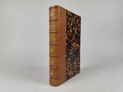 un livre brun posé sur une table à côté d'un mur blanc