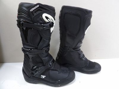 une paire de bottes de moto noires posée sur une table blanche