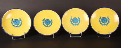 quatre assiettes jaunes ornées de motifs bleus, posées sur un fond noir