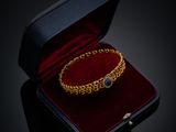 un gros plan sur un bracelet en or dans un écrin en velours rouge