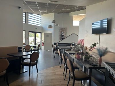 des tables et des chaises dans un restaurant, avec une télévision à écran plat accrochée au mur