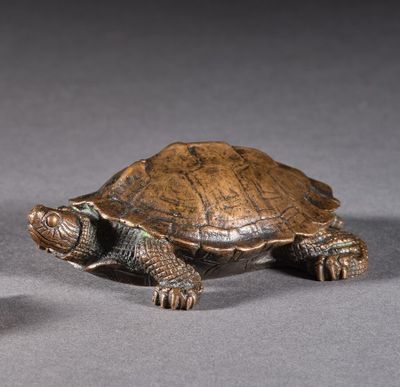 deux petites tortues en bronze assises l'une à côté de l'autre sur une surface grise