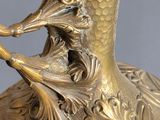 a gold vase with a bird on top of it