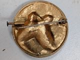 a gold pin with a picture of a man on it