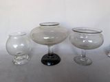 trois vases en verre posés l'un à côté de l'autre sur une table