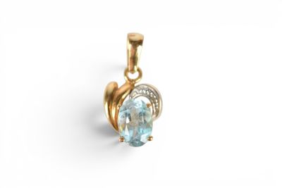 a close up of a gold pendant with a blue topaz stone