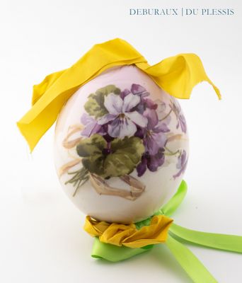 a decorated easter egg with flowers and a yellow ribbon