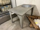 une table en béton sur laquelle se trouve un évier, dans une pièce