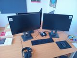 two monitors and a keyboard on a desk with headphones