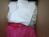 une boîte en carton remplie de vêtements et d'une couverture rose