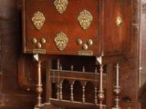 une petite armoire en bois ornée de décorations en laiton sur le dessus