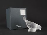 a glass bird that is sitting next to a box