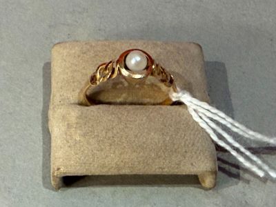 a gold ring with a pearl in it sitting on a box