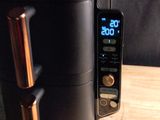 a black toaster sitting on a wooden table next to a cell phone