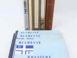 several books are stacked on top of each other on a white surface