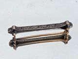 a silver and gold hair clip on a white surface