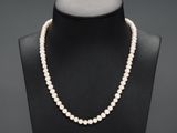 un collier de perles blanches sur un mannequin avec un fermoir en or