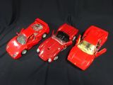 three red toy cars sitting next to each other on a black surface
