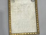 an old document with a gold frame on a white wall