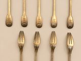 six forks are arranged in a row on a white surface