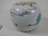 a white vase with colorful designs on it next to a small plate