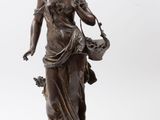 une statue antique en bronze représentant une femme tenant un panier de fleurs