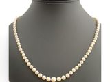 un collier de perles blanches sur un mannequin avec un fermoir en or