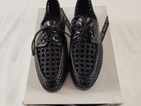 they are two pairs of black shoes on a box on a bed