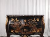 une photo d'une commode noire et dorée posée sur un parquet