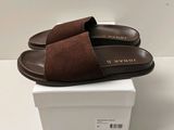 une paire de pantoufles marron posée sur une boîte blanche