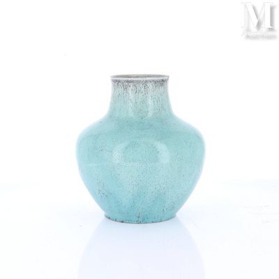 un petit vase bleu posé sur une surface blanche
