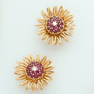 three gold and ruby flower brooches on a white surface