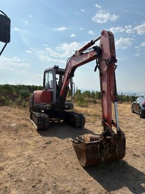 une pelleteuse rouge qui est à l'arrêt dans la terre