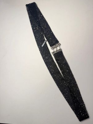 un gros plan d'un bracelet en perles noires posé sur une surface blanche