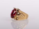 a close up of a gold ring with a red stone