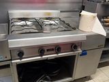 a stove in the middle of a kitchen with a bunch of dishes on the counter