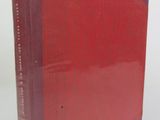 an old book with a red cover sitting on top of a white table