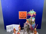 a small figurine of an elephant with people on it