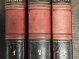 three old books sitting on a shelf next to each other