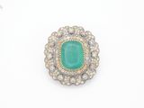 gros plan d'une bague avec une pierre verte entourée de diamants