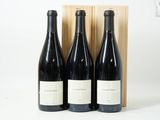 trois bouteilles de vin dans un coffret en bois sur une surface blanche